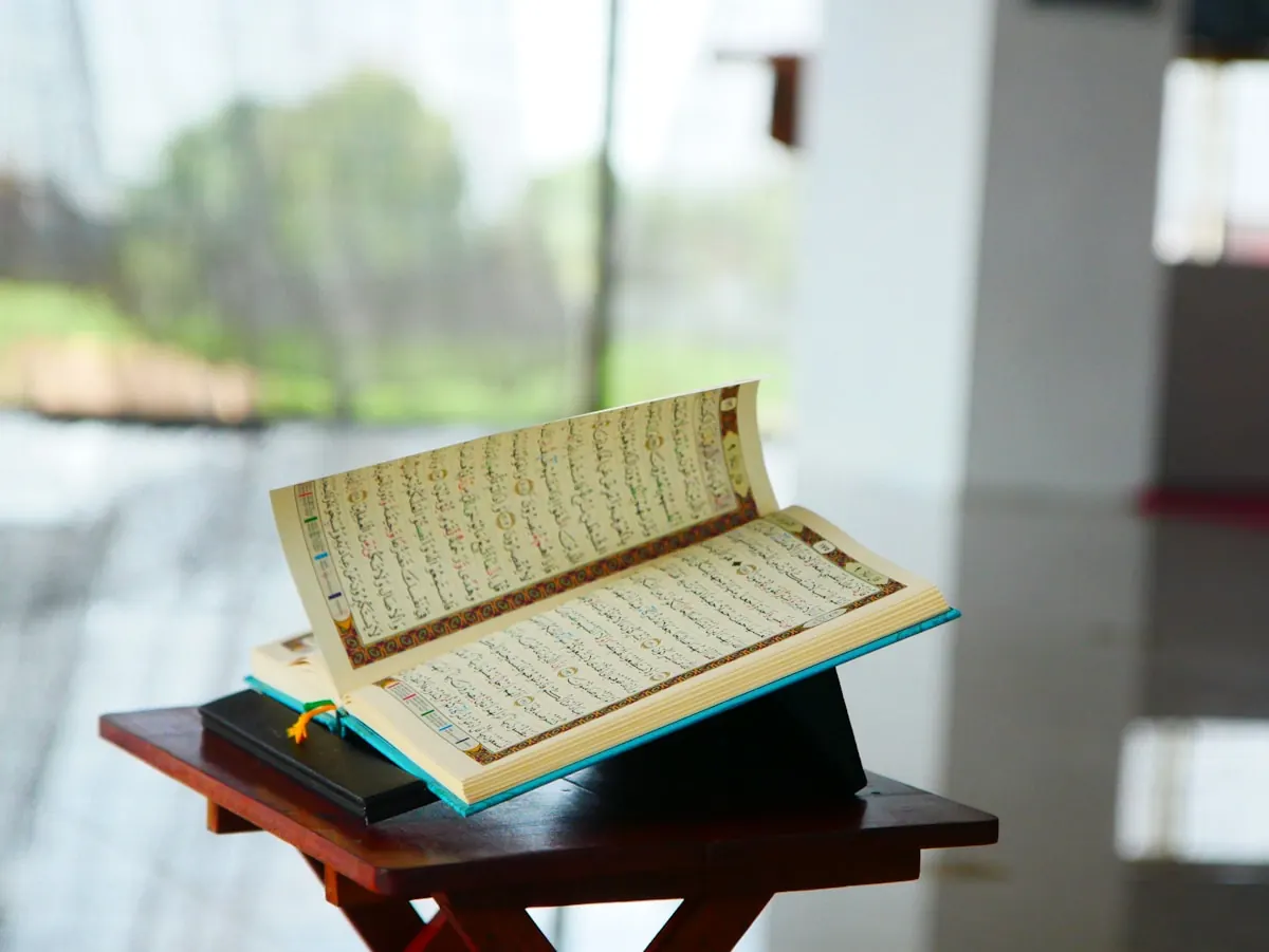 An open Quran rests on a raised wooden reading stand.