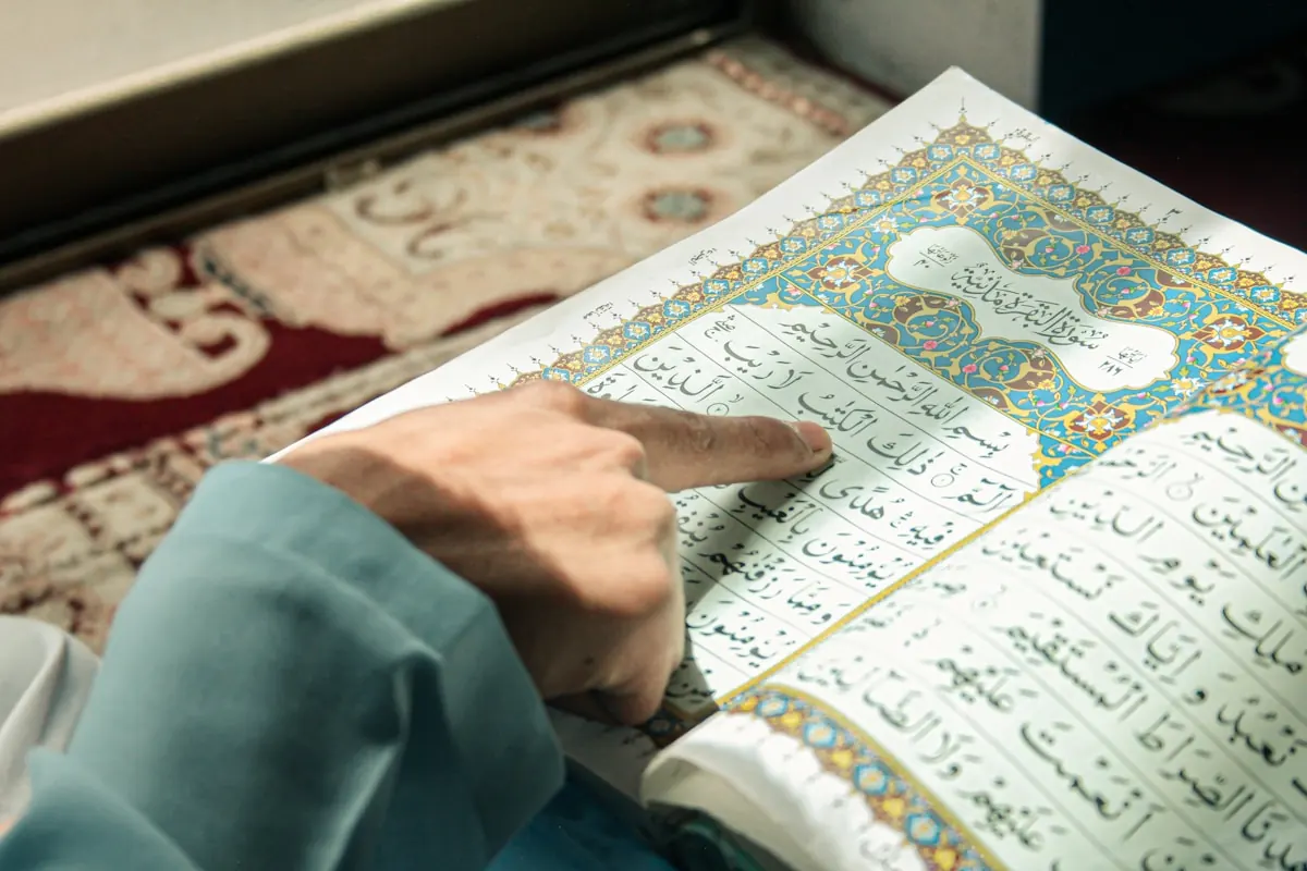 A reader follows a line of Quranic text with a finger.