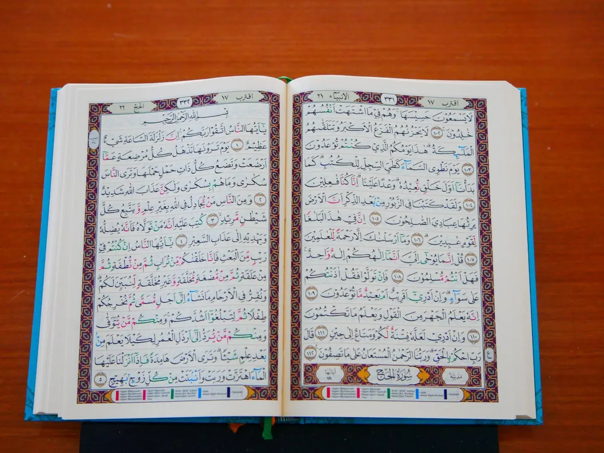 An open Quran showing colour-marked text on a wooden table.